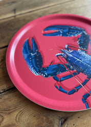 Plateau rond en bois d'un homard bleu sur fond rose