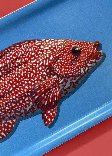 Petit plateau en bois d'un poisson rouge sur fond bleu