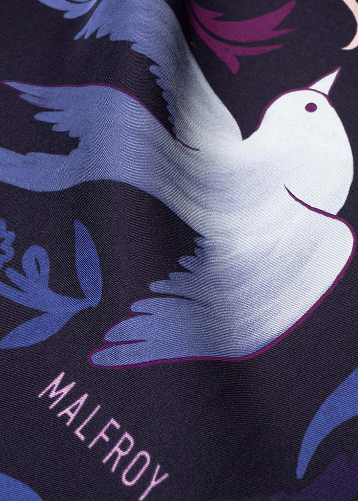 Détail d’un oiseau bleu et du logo Maison Malfroy sur le foulard Jardin d’hiver